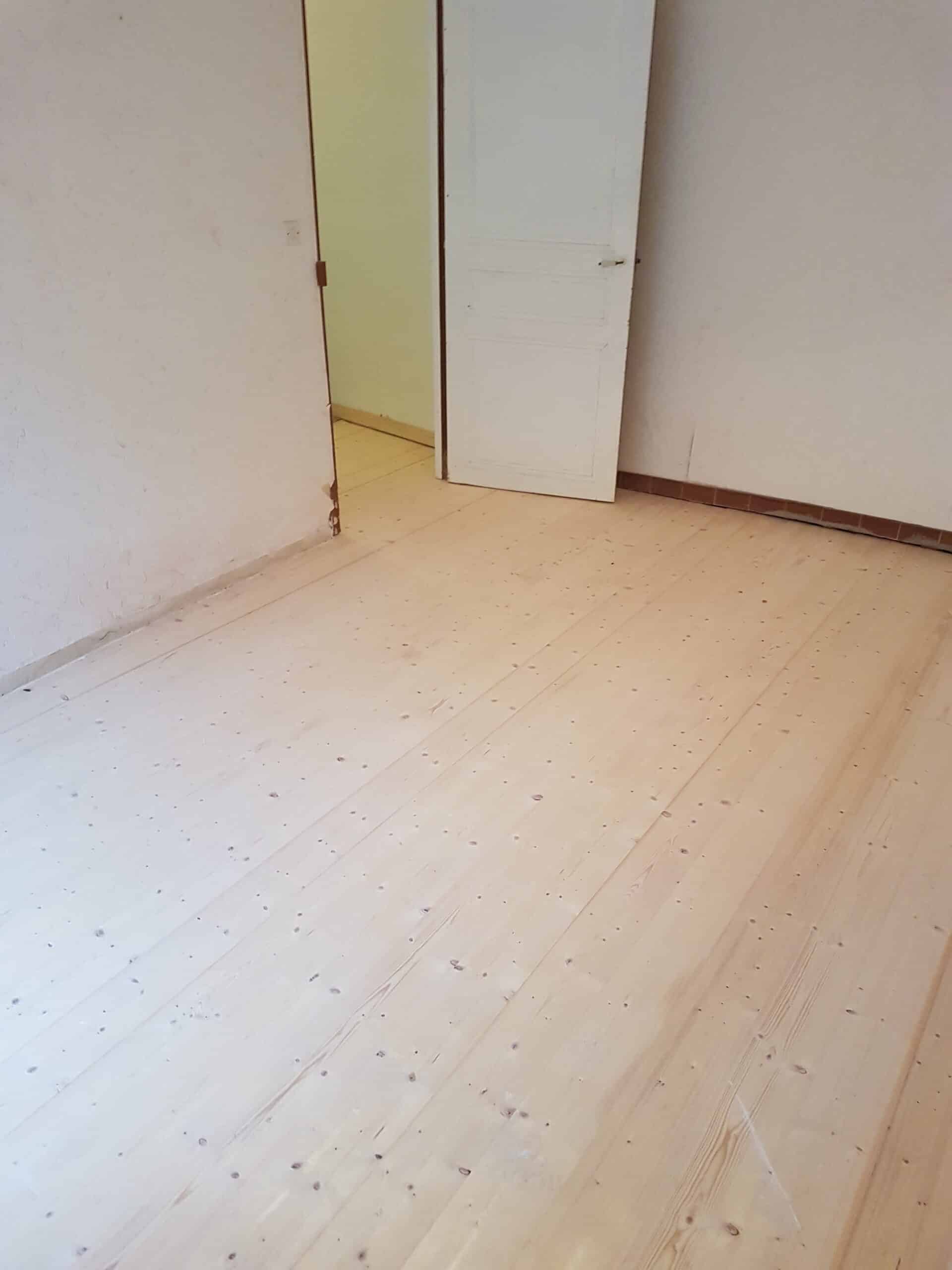 Ébéniste en action : Traçage de précision pour la menuiserie. Gros plan : ébéniste en tablier traçant des marques précises sur du bois brut à l'aide d'un crayon et d'une équerre. Maillet et copeaux sur l'établi.