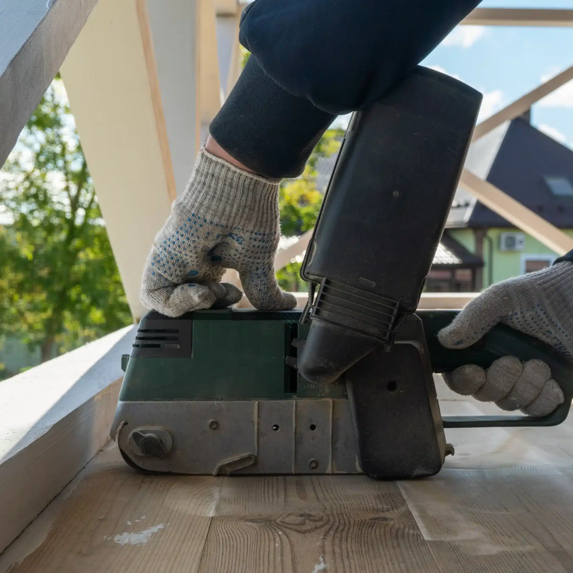 Ébéniste en action : Traçage de précision pour la menuiserie. Gros plan : ébéniste en tablier traçant des marques précises sur du bois brut à l'aide d'un crayon et d'une équerre. Maillet et copeaux sur l'établi.