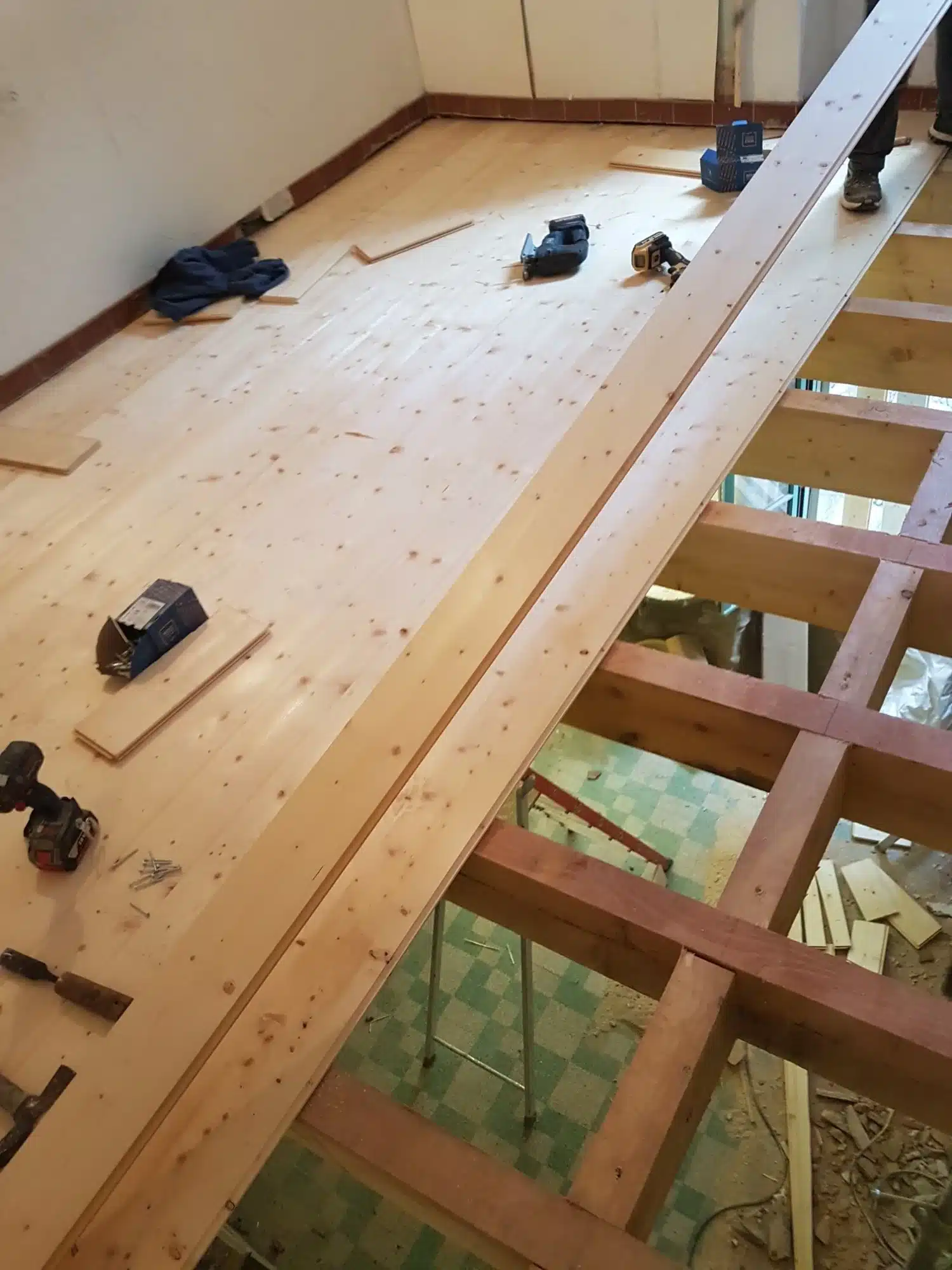 Ébéniste en action : Traçage de précision pour la menuiserie. Gros plan : ébéniste en tablier traçant des marques précises sur du bois brut à l'aide d'un crayon et d'une équerre. Maillet et copeaux sur l'établi.